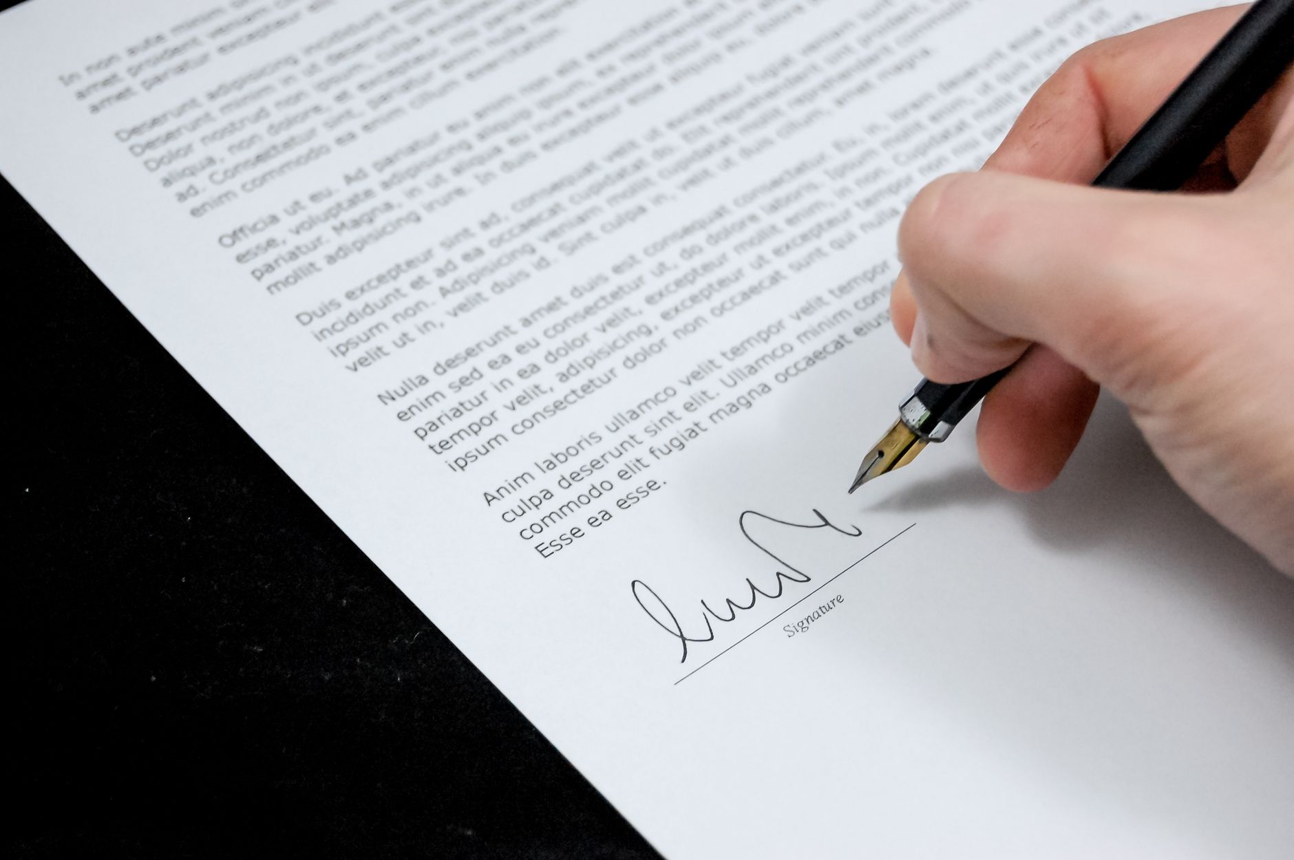 A hand signing a document with a fountain pen